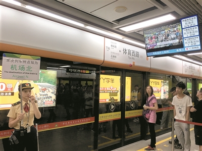 地鐵工作人員現(xiàn)場舉牌指引乘客乘坐貫通車