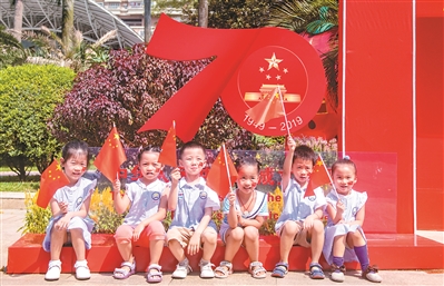 幼兒園的小朋友在“我和國旗同框”的布景前拍照。