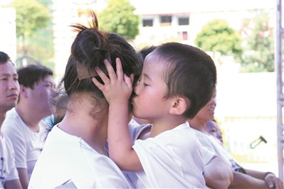 在廣州的一個“關(guān)愛留守兒童”主題的活動現(xiàn)場，孩子深情地親吻母親。（資料圖片）